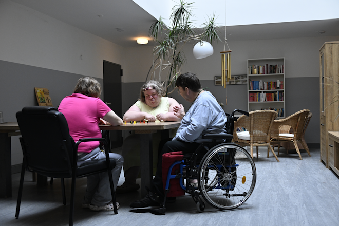 Bewohner des Wohn & Pflegeprojekts Lebenswert spielen gemeinsam an einem Tisch.